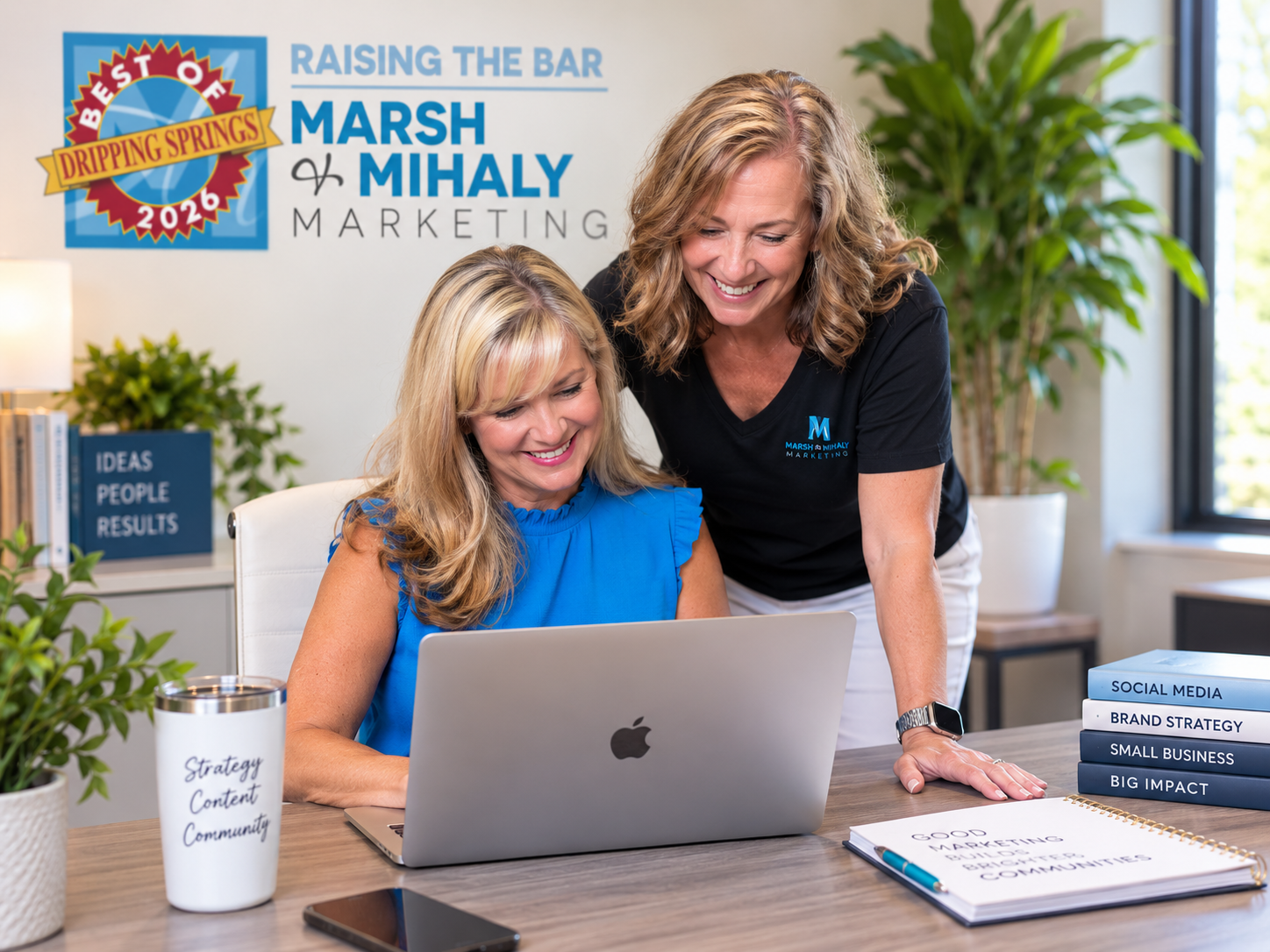 Dee Marsh and Dana Mihaly working together at a laptop in the Marsh & Mihaly Marketing office